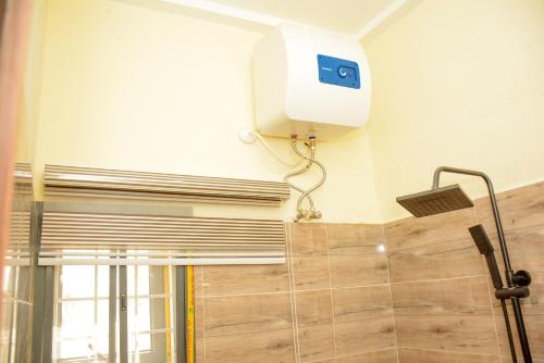 a shower in a bathroom with a thermostat on the wall at Dabras Homes in Kaduna