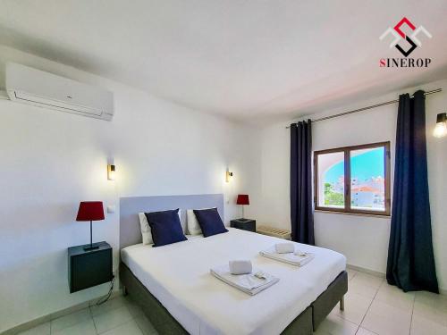 um quarto com uma grande cama branca com almofadas azuis em Apartamento T1 - Valmangude em Albufeira