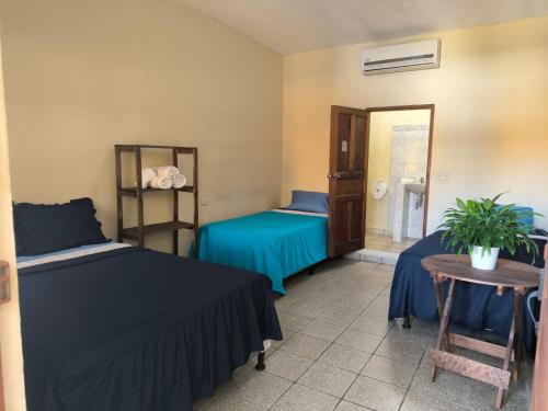Cette chambre comprend 2 lits, une table et un miroir. dans l'établissement Hotel y Restaurante Casa Jardines, à San Benito