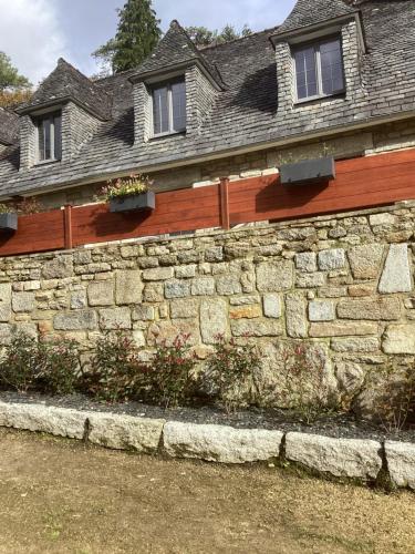 a stone wall in front of a house at Charmes de la Forêt in Huelgoat