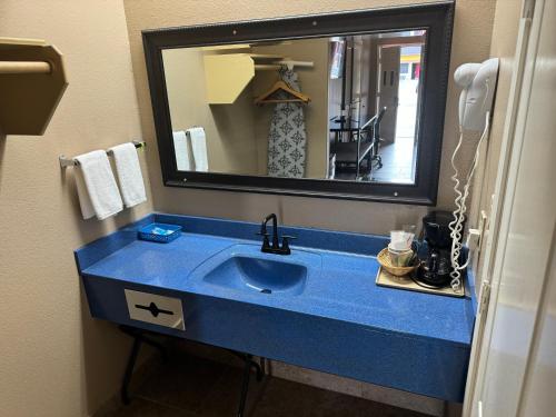 a bathroom with a blue sink and a mirror at Los Fresnos Inn and Suites in Los Fresnos