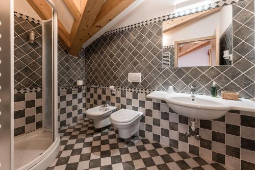 a bathroom with a sink and a toilet and a mirror at Hotel Sasso Rosso in Commezzadura