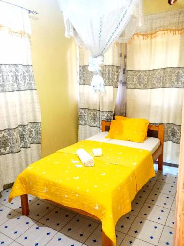 ein Schlafzimmer mit einem gelben Bett und einem Telefon darauf in der Unterkunft Motema AirBnB in Kisumu