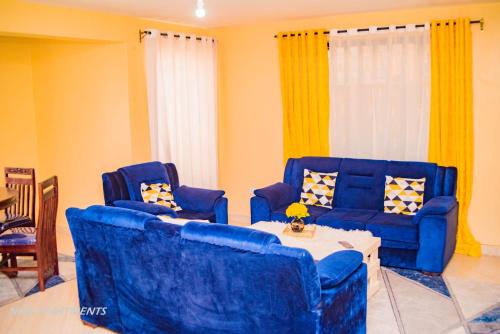 Duas cadeiras azuis e uma mesa numa sala de estar em Motema AirBnB em Kisumu