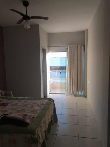 een slaapkamer met een bed en een groot raam bij Apartamento com VISTA MAR , no centro da Ilha de Guriri in São Mateus
