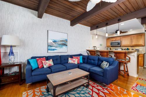 a living room with a blue couch and a kitchen at Kona Mansions 225 Top Floor 2 story Ocean views! in Kailua-Kona