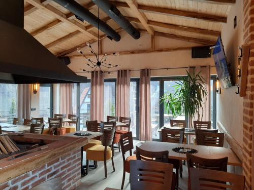 un restaurante con mesas, sillas y ventanas en Apartmani Sunce Stara planina, en Crni Vrh