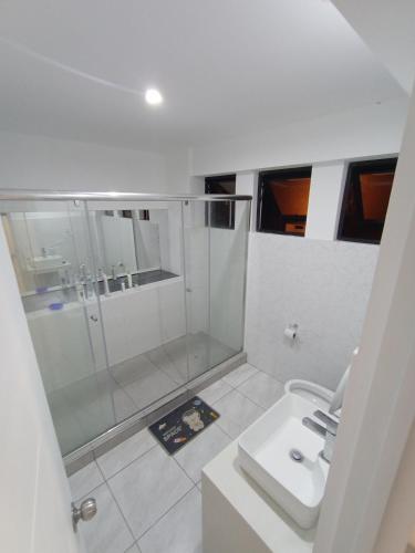 a white bathroom with a shower and a sink at Alquilo Casa playa in San Antonio