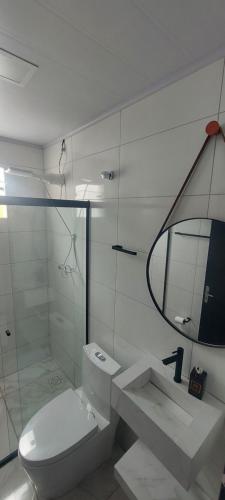 uma casa de banho branca com um WC e um espelho. em Casa Couto em Penha