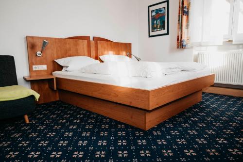 OberstadionにあるBrauereigasthof Adlerのベッドルーム1室(大型ベッド1台、木製ヘッドボード付)