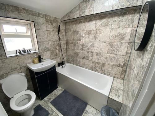 a bathroom with a tub and a toilet and a sink at Spacious 3 Bed House London in Thornton Heath