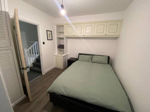 a small bedroom with a bed and a staircase at Spacious 3 Bed House London in Thornton Heath