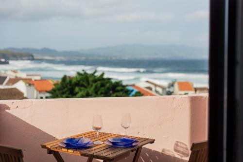 two glasses of wine sitting on a table on a balcony at Azorean Ocean House - Terrace with Sea View in Ribeira Grande