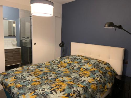 een slaapkamer met een bed met een bloemenbed bij Appartement en RDC chaleureux à 100m des plages et du centre ville in Concarneau