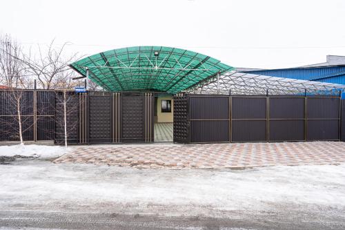 a garage with a fence and a green roof at Guest house "Halif" in Tegizchil