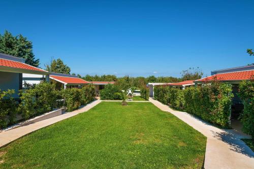 a garden with green grass and bushes and buildings at Mobile Homes Rocco 2 in Banjole