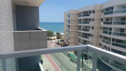 a balcony with a view of a building and the ocean at Studio pé na areia, vista, internet e ar in Macaé