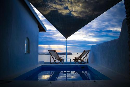 two chairs and a swimming pool with a view of the ocean at Irenes View Apartments in Agia Irini Paros
