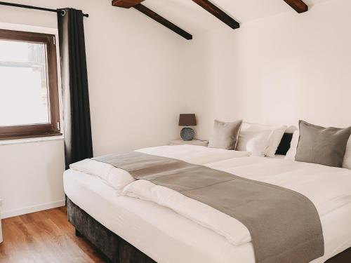 a large white bed in a room with a window at Dorf 70 in Eichenberg