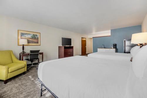 una habitación de hotel con 2 camas y una silla amarilla en Seaport Inn & Suites, en Lewiston
