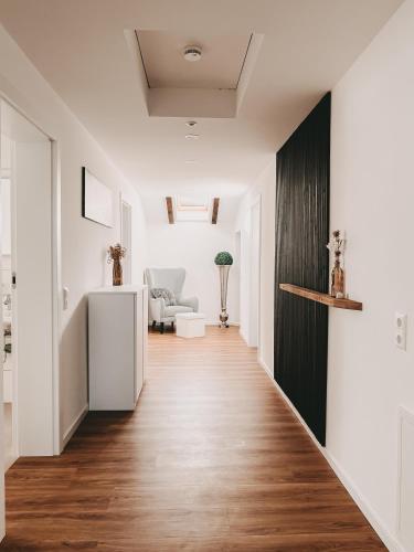 a hallway with white walls and a wooden floor at Dorf 70 in Eichenberg