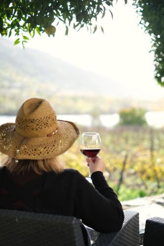a woman in a hat holding a glass of wine at Quinta das Casas - Douro Winery & Villas in Vila Real