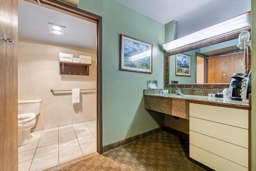 a bathroom with a toilet and a sink and a mirror at Seaport Inn & Suites in Lewiston