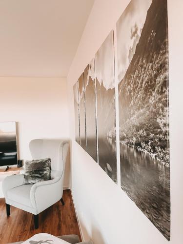 a living room with a white chair and pictures on the wall at Dorf 70 in Eichenberg