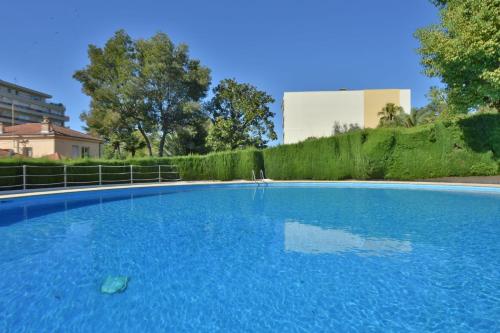 ein großer blauer Pool mit einem Gebäude im Hintergrund in der Unterkunft Close to downtown Cannes swimming pool and sea view in Cannes