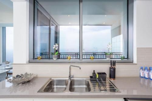 een keuken met een wastafel en 2 ramen bij Waves Holiday Homes - Sea View Luxury 3 Bedroom Apartment With Balcony in Dubai