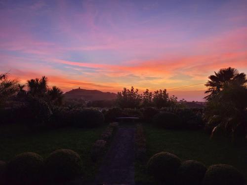 a sunset over a field with a dirt road at Traumgarten - Rustic House - Sunset & SeaView in Várzea