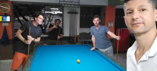 a group of men playing a game of pool at Hostel Metro Floresta Alojamiento in Medellín