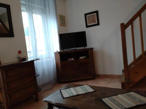 een woonkamer met een tv en een tafel bij La Molette - 4 personnes in Saint-Julien-Molin-Molette