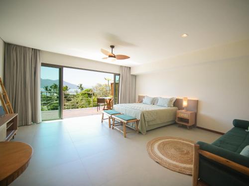 a bedroom with a bed and a living room with a couch at Hotel Velas do Engenho in Ilhabela