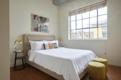 a white bedroom with a large bed and a window at Constance Lofts by Black Swan in New Orleans
