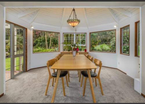 a dining room with a wooden table and chairs at Horse Shoe Manor in Paihia
