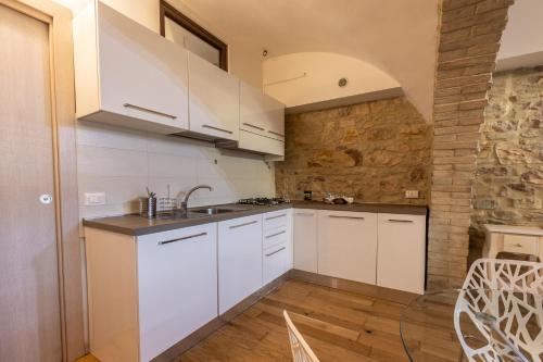 a kitchen with white cabinets and a stone wall at Lo Scrigno degli Angeli in Santa Maria degli Angeli