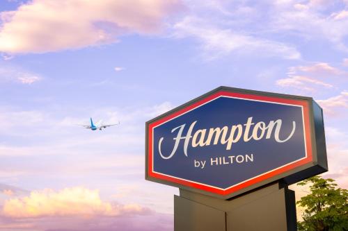 a sign for a hampton motel with an airplane at Hampton By Hilton Guanacaste Airport in Liberia