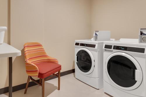 a laundry room with a washing machine and a chair at Hampton By Hilton Guanacaste Airport in Liberia