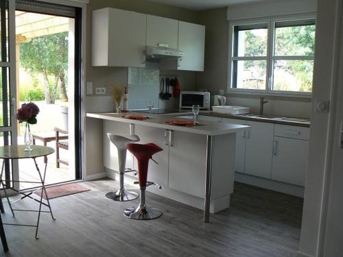 uma cozinha com armários brancos e um balcão com um banco em VANNES STUDIO RECENT AU CALME em Vannes