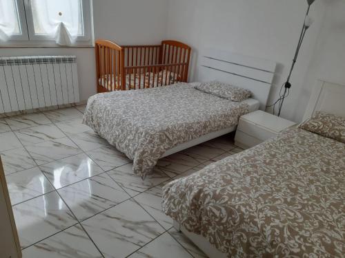 a bedroom with two beds and a tiled floor at Villa Azzurra in Monfalcone