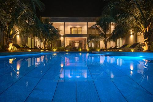 a large swimming pool with palm trees in front of a building at Résidence Gabriel in Sali Nianiaral