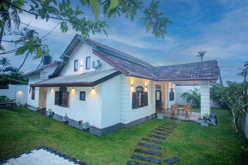 a small white house with a pathway at Villa RISITHENMI in Ahangama