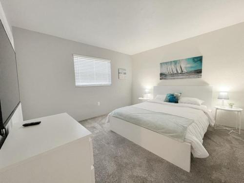 a white bedroom with a large bed and a window at Beautiful Waterfront Beach Condo With Dock in St. Pete Beach