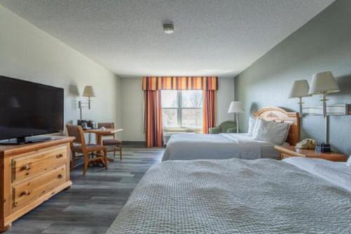 a hotel room with two beds and a flat screen tv at Lancaster Inn & Suites in Manheim