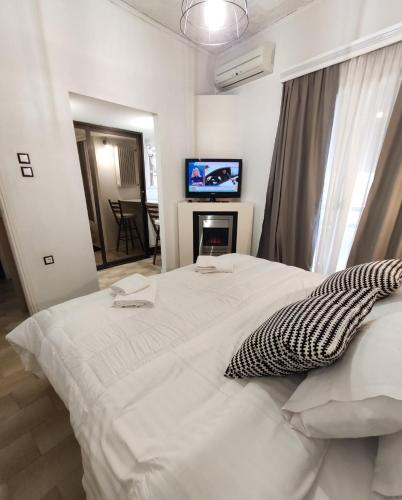 Schlafzimmer mit einem weißen Bett, einem Kamin und einem TV in der Unterkunft Johnny's loft 2 in Agrinio