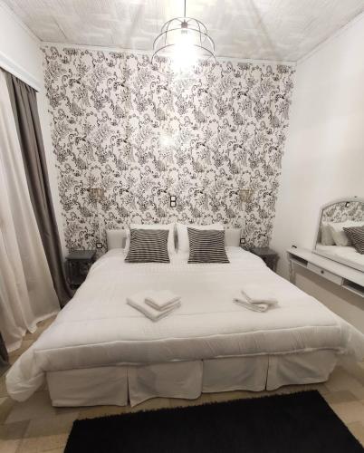 een slaapkamer met een groot wit bed met bloemenbehang bij Johnny's loft 2 in Agrinion