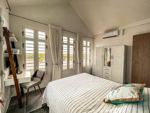 1 dormitorio con cama, escritorio y ventana en Kas di LamanBlu, en Kralendijk