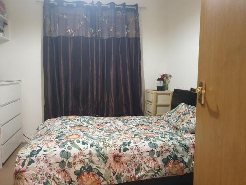 1 Schlafzimmer mit einem Bett mit Blumenbettdecke in der Unterkunft The Hidden Gem in Watford