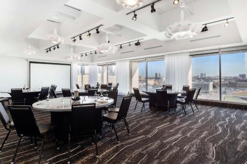 a dining room with tables and chairs and large windows at Lorenzo Hotel Dallas, Tapestry Collection by Hilton in Dallas